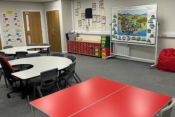 Ystafell dosbarth lliwgar gyda byrddau a cadeiriau