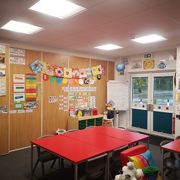 bwrdd coch gyda chadeiriau mewn ystafell ddosbarth