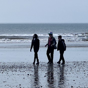 3 students walkimg next to the sea