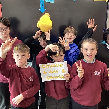 Ysgol Tywyn pupils holding a 'Chwilio am chwid' poster